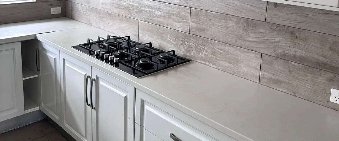 A finished kitchen with a gas cooktop and stone benchtop